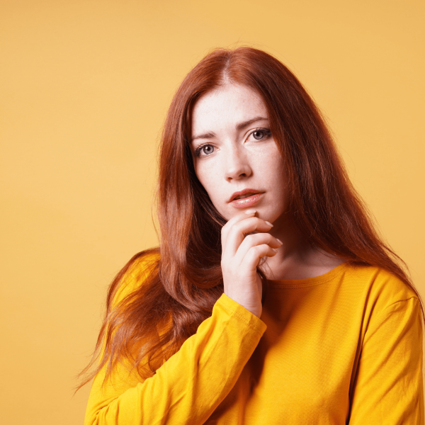 a person with red hair posing against a yellow background