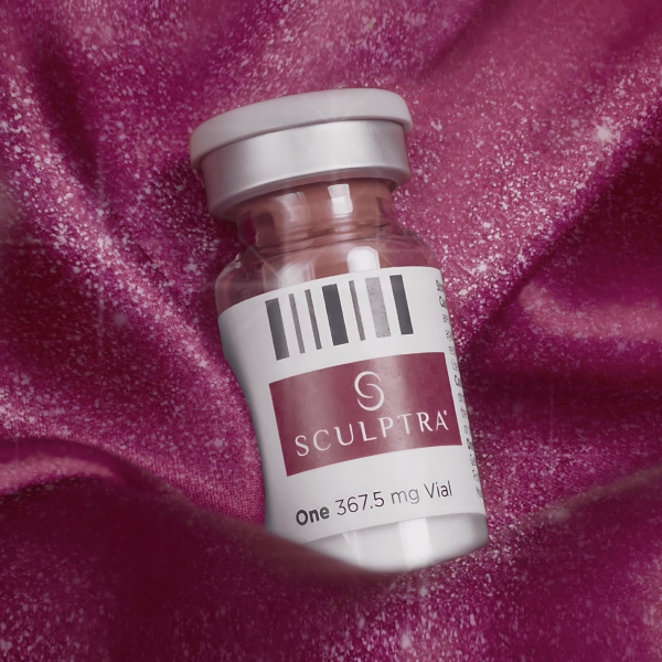 a vial of liquid sitting on top of a pink fabric