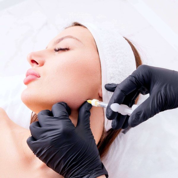 a womans face getting a dysport injection procedure on her jawline 2